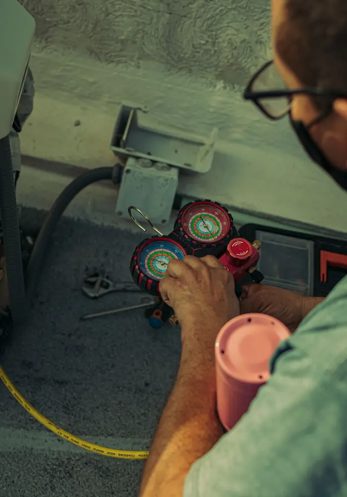 Técnico medindo pressão com manifold durante recarga de gás
